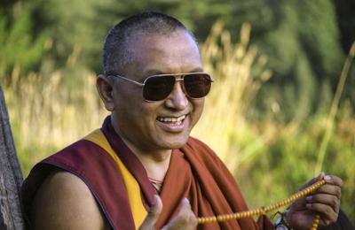 Lama Zopa Rinpoche holding a mala and wearing sunglasses, date and location unknown.